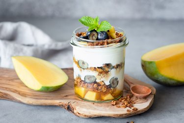 Breakfast yogurt parfait with granola, mango, berries in jar