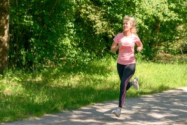 Woman Running On Footpath While Exercising In Park