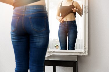 woman checking her belly button in front of the mirror
