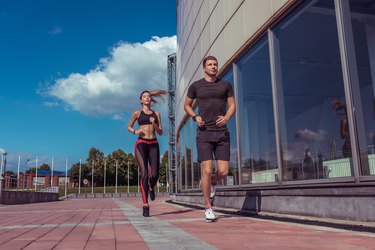 Athletic couple man and girl in summer city, run on morning run, burning calories, cardio fitness training day and morning. Healthy lifestyle style. Sportswear, friends and relationships are paired.