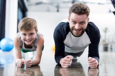 Man and boy doing plank exercise at fitness center