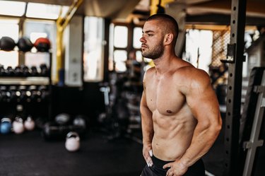 Man standing in gym about to do a shoulder workout.