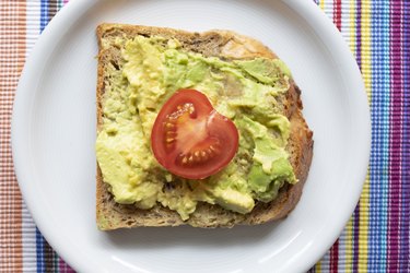 Whole-wheat toast with avocado and tomato on a white plate to lower blood sugar at night