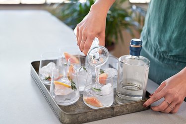 Anonymous woman's hands pouring drinks into glasses in a drinks tray