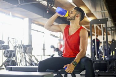 Young muscular man drinking a pre-workout supplement drink at the gym