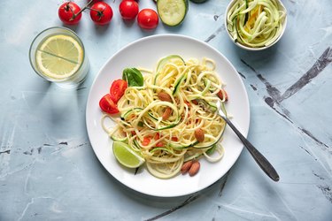 Plate of spaghetti with zucchini on table