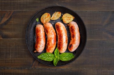 Grilled brat sausages in frying pan on wooden table