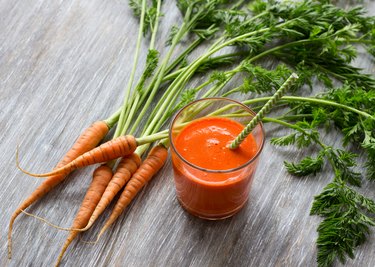 Glass of freshly squeezed juice from a young carrot on a wooden table