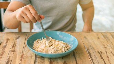 Men eating spaghetti with creamy cheese sauce.