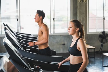Young couple exercising by running on the treadmill to maintain good health