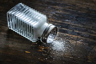 Salt shaker on rustic wooden table. Copy space.