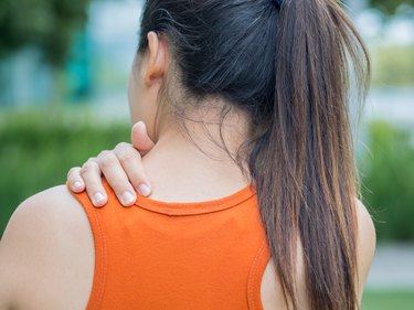 Closeup sport woman feel pain on her neck and shoulder, health care concept.