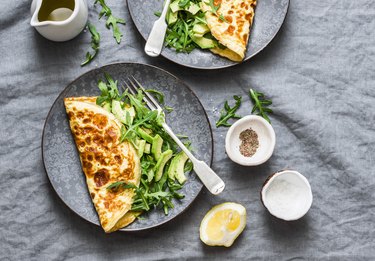 Omelette with cream cheese, arugula and avocado salad on a grey background, top view.  Healthy breakfast or diet lunch