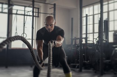 Mature strong man doing battle rope exercises during a CrossFit MetCon workout