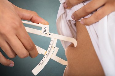 Woman Checking Stomach Fat With Caliper