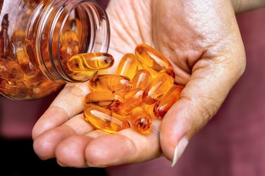 Woman holding fish oil capsules in hand. Fish oil capsules as a dietary supplement containing omega-3 and vitamin a is high for health care.