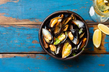 Mussels in clay bowl, glass of white wine and lemon