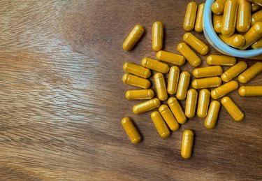 Top view Turmeric or Curcumin capsules are on a brown wood table