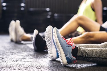 Ankles of athletes sitting on floor in gym