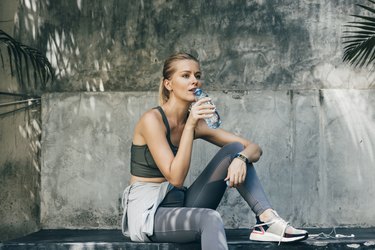 Female jogger sitting at a park and drinking water