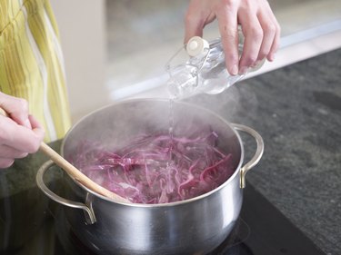 Pouring white vinegar onto red cabbage