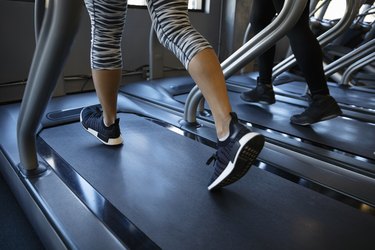 Legs of woman walking on treadmill in gym