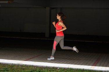 Female runner jogging trough parking lot.