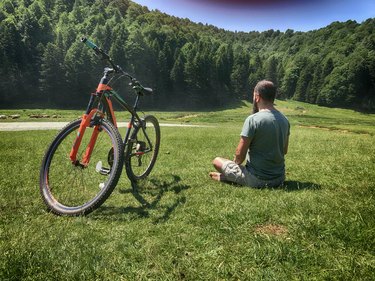 Man practicing yoga for cyclists next to his bike outdoors