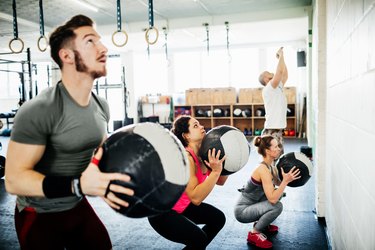 People doing an EMOM workout with medicine balls at a CrossFit box