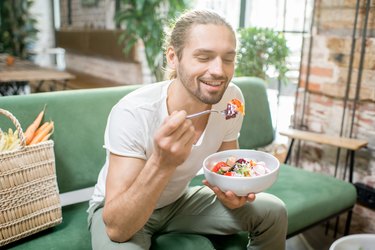 Vegetarian man eating salad indoors for low carb foods and low fat foods