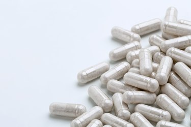 Heap of white capsules medications on white background