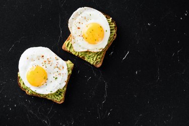 Fried egg and mashed avocado on toasted bread in daily cholesterol intake