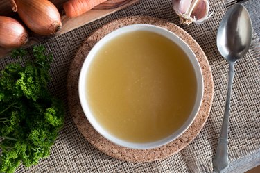 Chicken bone broth with vegetables in the background, as an example of a hangover cure