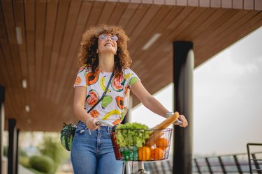 A person smiling while pushing a bicycle with fresh fruit in the basket, to help them drop 30 pounds.