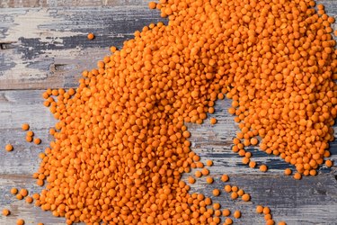 Background pattern with orange lentils seeds of annual legume plant, vegetable protein, flat lay.