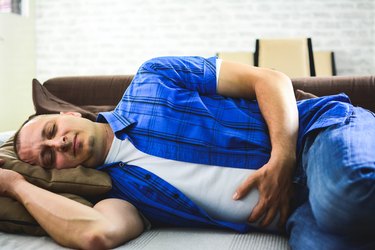Man lying on sofa looking sick in the living room