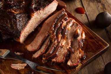 Homemade smoked and slow-cooked Beef Brisket sliced up on a wooden cutting board