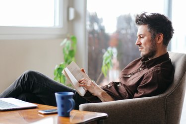 Young man reading a book at home for his health goals list