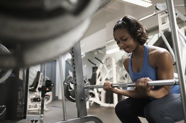 Woman doing barbell biceps curls at the gym