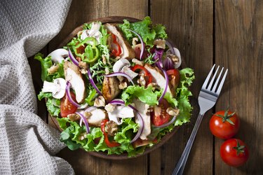 Grilled chicken salad shot from above on rustic wood table