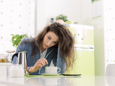 Tired woman having breakfast at home