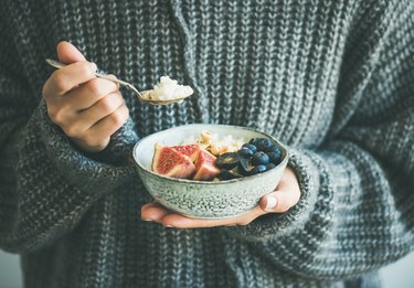 Woman in woolen sweater eating rice coconut porridge