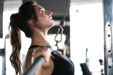 Woman strength training in weight room with confidence.