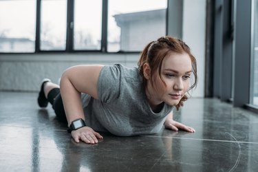Obese girl performing push ups in gym