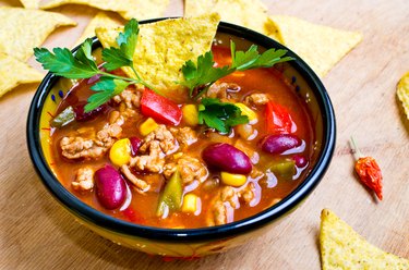 Tortilla soup in a bowl garnished with fresh cilantro on wooden table.