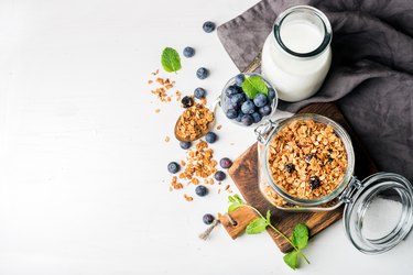 Healthy breakfast ingredients. Homemade muesli in open glass jar, milk