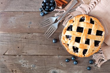 Blueberry pie, top view corner border over a rustic wood background