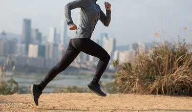 Female runner running on mountains next to modern city