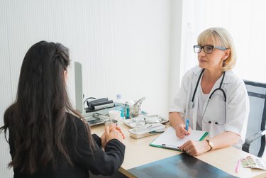 Senior female doctor meet the patient discussing and making notes about symptom problem. Health care and client service in medicine concept.