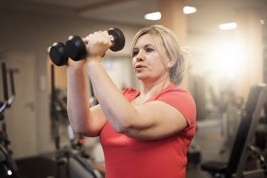 Woman doing upper-body workout at the gym to burn fat